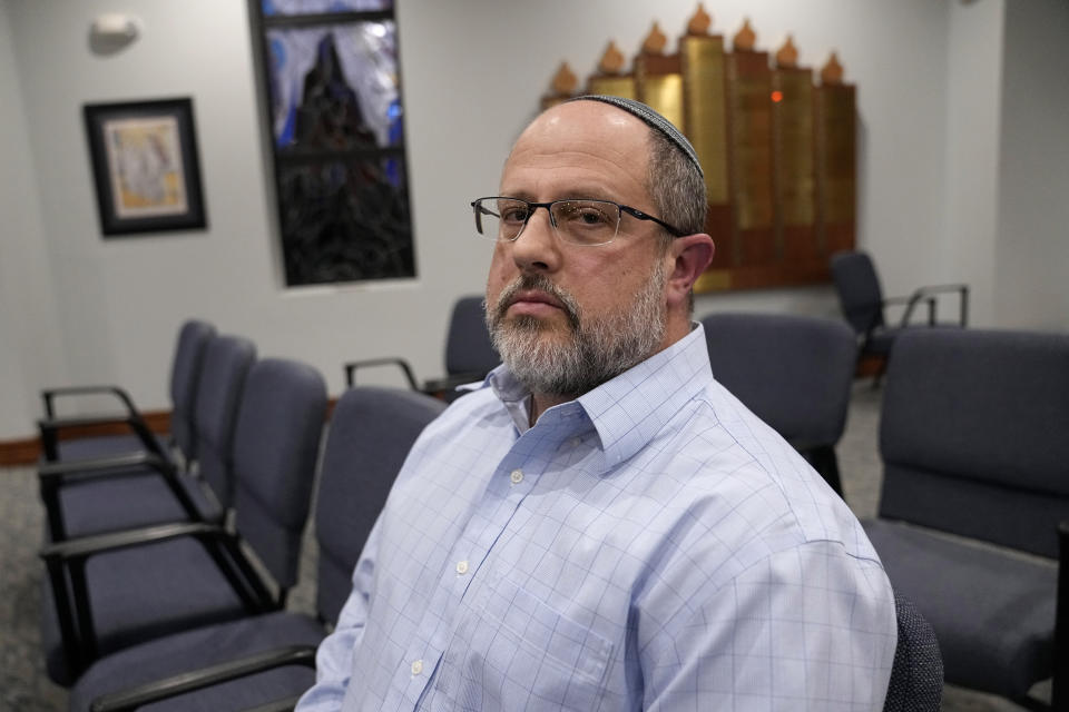 In this Dec. 22, 2022, photo, Shane Woodward poses for a photo in the area of Congregation Beth Israel where he was sitting when taken hostage in Colleyville, Texas. A year ago, a rabbi and three others survived a hostage standoff at their synagogue in Colleyville, Texas. Their trauma did not disappear, though, with the FBI's killing of the pistol-wielding captor. Healing from the Jan. 15, 2022, ordeal is ongoing. (AP Photo/Tony Gutierrez)