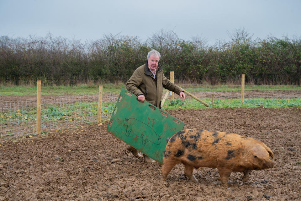 Jeremy Clarkson standing on a farm with a pig