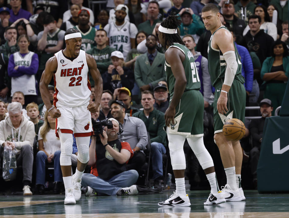 Miami Heat forward Jimmy Butler (22) reacts in front of Milwaukee Bucks' Jrue Holiday (21) and Brook Lopez during the second half of Game 5 in a first-round NBA basketball playoff series Wednesday, April 26, 2023, in Milwaukee. The Heat won 128-126 in overtime, eliminating the Bucks from the playoffs. (AP Photo/Jeffrey Phelps)