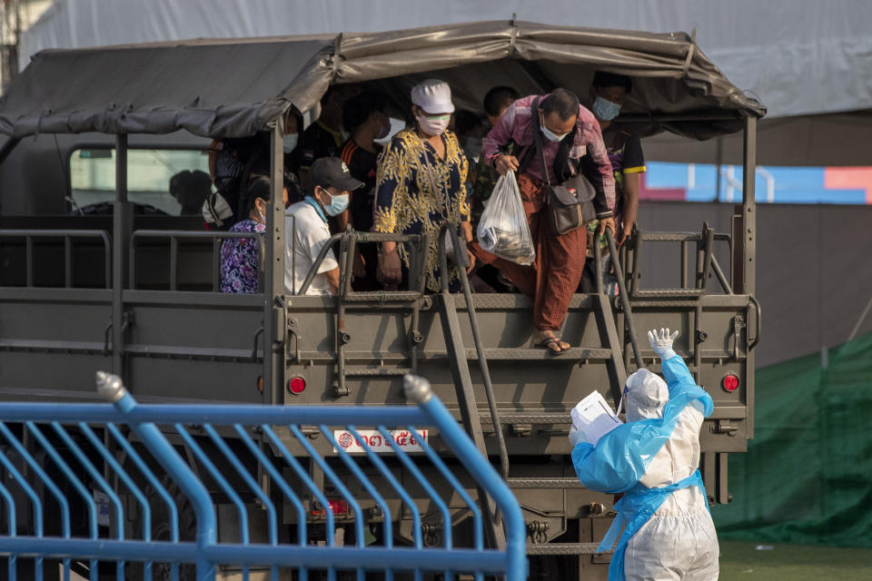 A medical worker in personal protective clothing gestures as migrant workers arrive at a field hospital for COVID-19 patents in Samut Sakhon, South of Bangkok, Thailand, Monday, Jan. 4, 2021. For much of 2020, Thailand had the coronavirus under control. After a strict nationwide lockdown in April and May, the number of new local infections dropped to zero, where they remained for the next six months. However, a new outbreak discovered in mid-December threatens to put Thailand back where it was in the toughest days of early 2020. (AP Photo/Gemunu Amarasinghe)