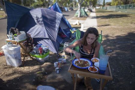 Stacie McDonough, 51, eats lunch by her tent in a homeless RV and tent encampment near LAX airport in Los Angeles, California, United States, October 26, 2015. REUTERS/Lucy Nicholson