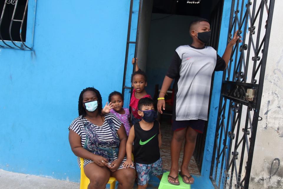 FILE - In this April 14, 2020 file photo, a family waits outside their home to receive food handouts from the local government, in the Cristo del Consuelo neighborhood of Guayaquil, Ecuador. In March and April, Guayaquil was a pandemic hellscape of makeshift morgues, hundreds dying at home, bodies left in the street. But Guayaquil has stabilized since then, sending medical teams and equipment elsewhere in Ecuador and taking in virus patients from outside the city. (AP Photo/Angel de Jesus, File)