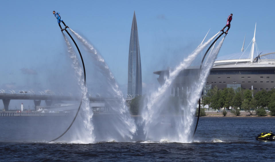 Members of the Russian hydroflight team perform during the Day of Russia celebration in St.Petersburg, Russia, Friday, June 12, 2020, with business tower Lakhta Centre, the headquarters of Russian gas monopoly Gazprom and Gazprom Arena soccer stadium in the background. (AP Photo/Dmitri Lovetsky)