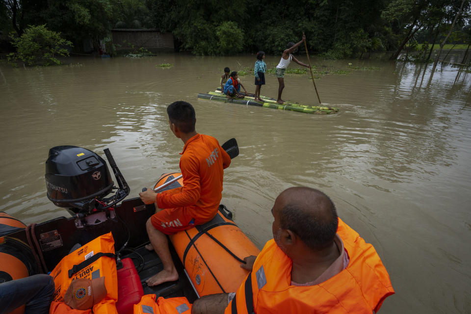 Villagers move on a banana raft past National Disaster Response Force (NDRF) personnel in the flooded Korora village, west of Gauhati, India, Friday, June 17, 2022. (AP Photo/Anupam Nath)