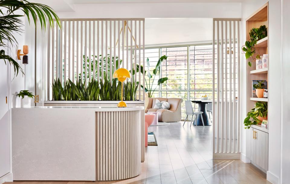 Slatted partitions allow the natural light from the waiting room to flood the reception area, and a sunny yellow lamp by Verner Panton greets patients.