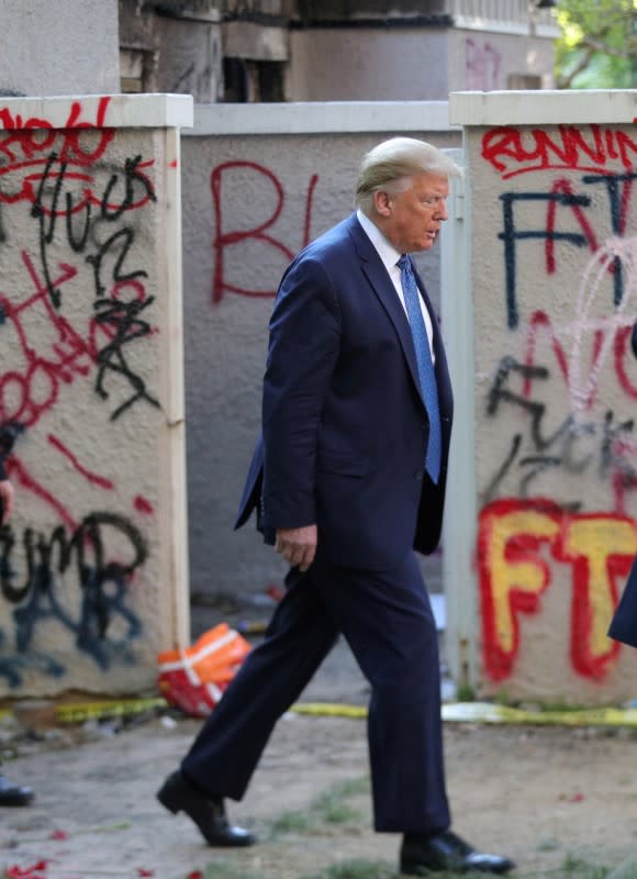 FILE PHOTO: U.S. President Trump walks past a building defaced with graffiti by protestors in Washington