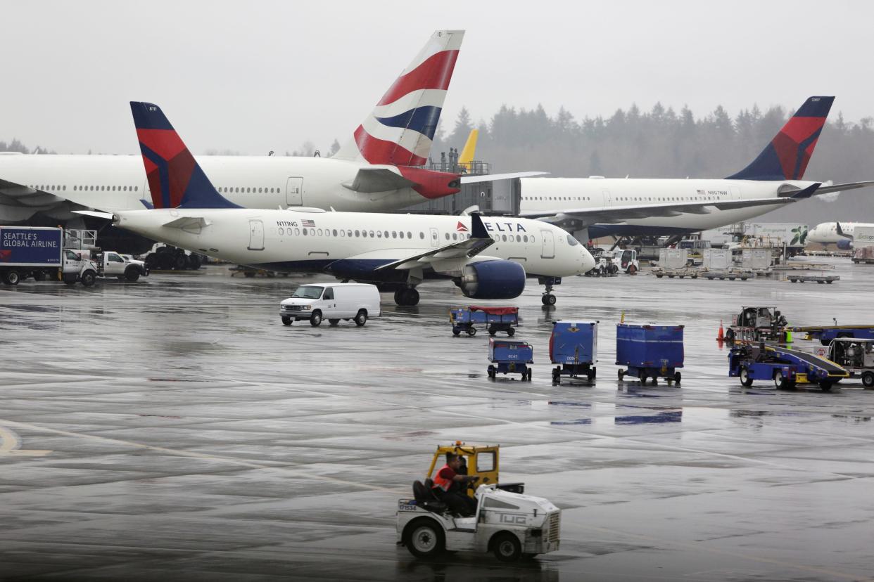 FILE PHOTO: Delta Airlines planes and a British Airways plane (2nd L) are pictured at Seattle-Tacoma International Airport, on the day Delta CEO Ed Bastian told employees he was cutting 40% of capacity in the coming months, the largest in the airline's history, in addition to pursuing aid, in SeaTac, Washington, U.S. March 13, 2020.  REUTERS/Jason Redmond/File Photo