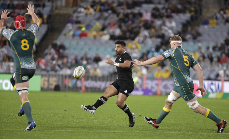 New Zealand's Richie Mo'unga, center, kicks between Australian defenders Harry Wilson, left, and Matt Philip during their Bledisloe rugby test match at Stadium Australia, Sydney, Australia, Saturday, Oct. 31, 2020. (AP Photo/Rick Rycroft)