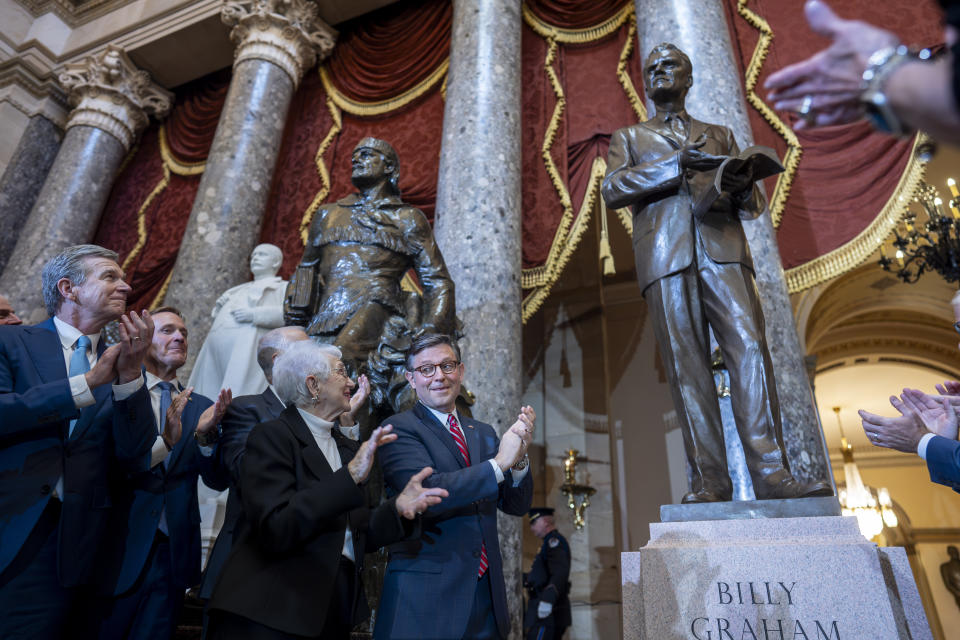 From left, North Carolina Gov. Roy Cooper, Sen. Ted Budd, R-N.C., Rep. Virginia Foxx, R-N.C., and Speaker of the House Mike Johnson, R-La., applaud as they unveil a bronzed sculpture of the late Rev. Billy Graham is unveiled at the U.S. Capitol in Washington, where it will stand on behalf of his native North Carolina, Thursday, May 16, 2024. Known as America's pastor, Graham died in 2018 at age 99. (AP Photo/J. Scott Applewhite)