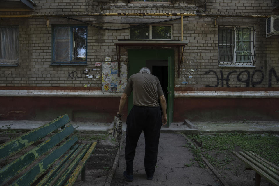 Seventy-year-old pensioner Valerii Ilchenko, who lives alone and is refusing to evacuate, walks to his apartment, after filling out his daily crossword, in Kramatorsk, eastern Ukraine, Wednesday, July 6, 2022. Now a widower, Ilchenko says he still has no intention of leaving. "I don't have anywhere to go and don't want to either. What would I do there? Here at least I can sit on the bench, I can watch TV," he says in an interview in his single-room apartment. (AP Photo/Nariman El-Mofty)
