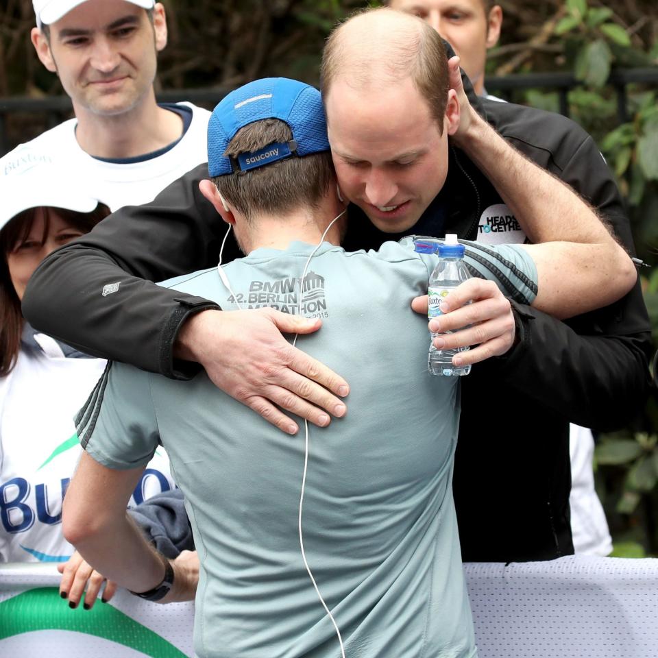The Duke of Cambridge hugs a runner as he hands out water  - Credit: Chris Jackson/PA Wire