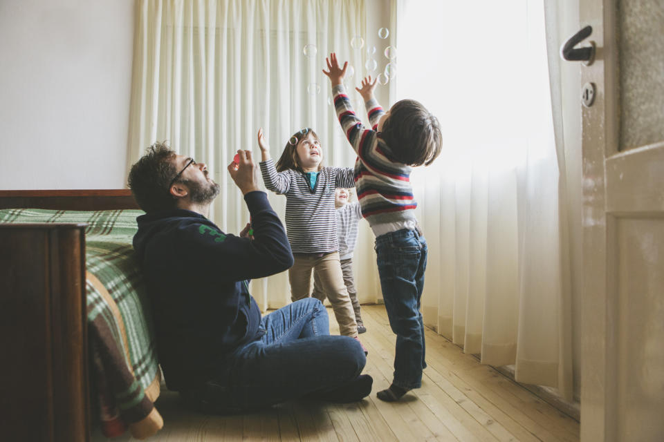 A man playing with bubbles with children