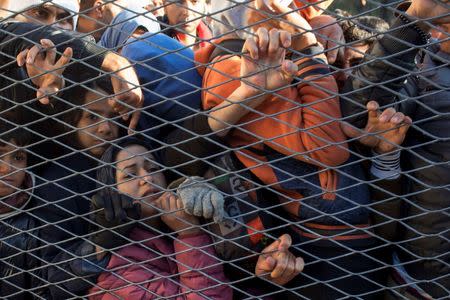 Migrants stand behind a gate as they wait to board buses inside a registration camp in Opatovac, Croatia September 23, 2015. REUTERS/Marko Djurica