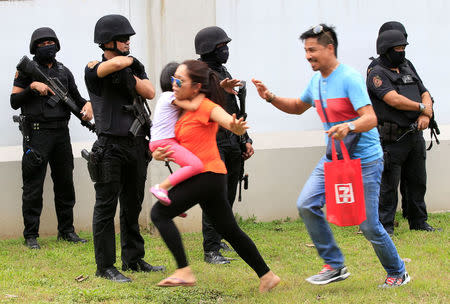 Pedestrians move away quickly as Special Weapons and Tactics (SWAT) team members prepare tear gas to disperse various activist and Indigenous People's (IP) groups protesting against the continuing presence of US troops in the Philippines in front of the U.S. Embassy in metro Manila, Philippines October 19, 2016. REUTERS/Romeo Ranoco