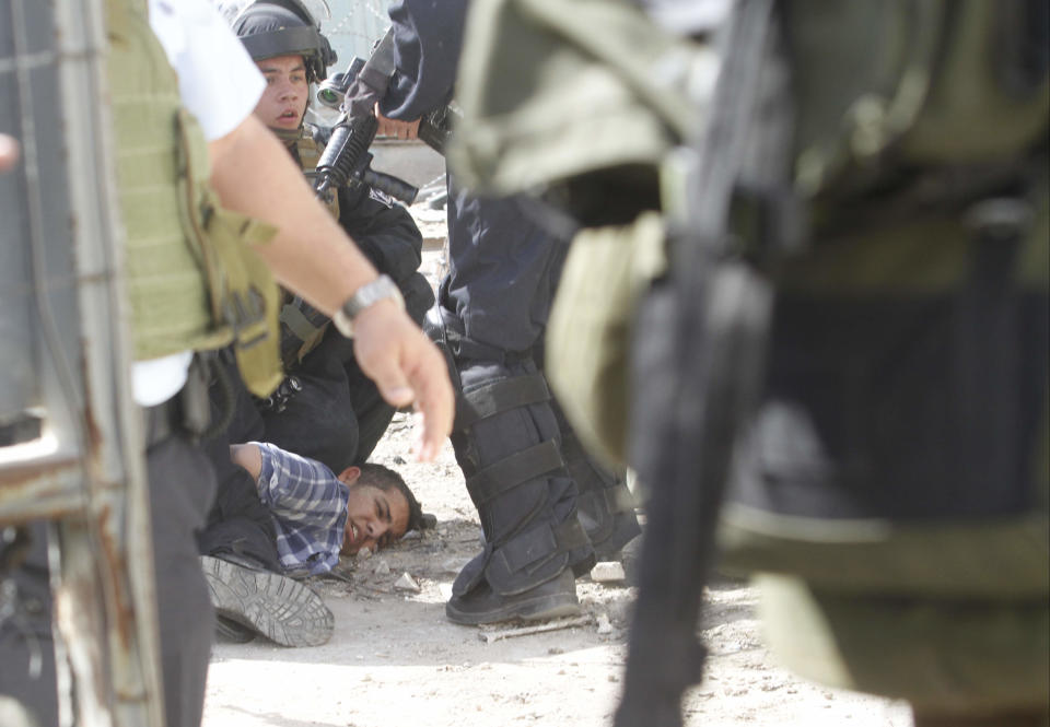 A Palestinian is arrested by Israeli soldiers in the centre of the West Bank city of Hebron, Friday, Feb. 21, 2014, during a demonstration against the closure of the main downtown street. Shuhada street was shut after a 1994 mosque massacre when a settler shot and killed 29 Muslim worshippers. The military closed it citing security reasons. (AP Photo/Nasser Shiyoukhi)