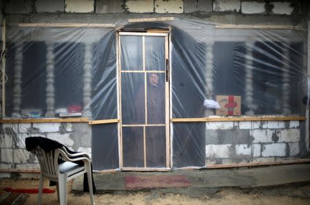 A Palestinian woman looks through her dwelling covered with plastic sheet in Khan Younis in the southern Gaza Strip. REUTERS/Ibraheem Abu Mustafa