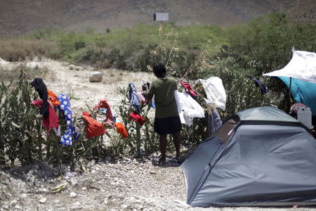 A woman picks up dry laundry at a camp for returned Haitians and Haitian-Dominicans, near the border between the Dominican Republic and Haiti, in Malpasse, August 3, 2015. REUTERS/Andres Martinez Casares