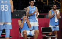 El argentino Luis Scola (4) se cubre la cara con la camiseta mientras recibe una emotiva ovación de su equipo, de sus rivales australianos y de los demás presentes en la cancha al sentarse en la banca en los últimos instantes del juego de cuartos de final del torneo olímpico entre los dos países, el último del alero argentino, el 3 de agosto de 2021, en Saitama, Japón. (AP Foto/Eric Gay)