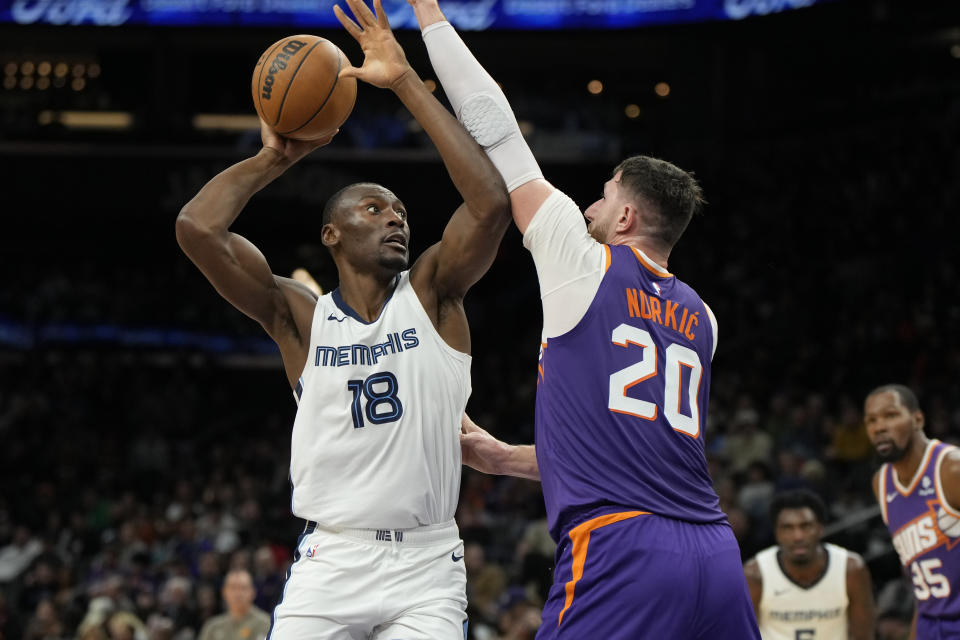 Memphis Grizzlies center Bismack Biyombo, left, shoots over Phoenix Suns center Jusuf Nurkic (20) during the second half of an NBA basketball game, Sunday, Jan. 7, 2024, in Phoenix. (AP Photo/Rick Scuteri)