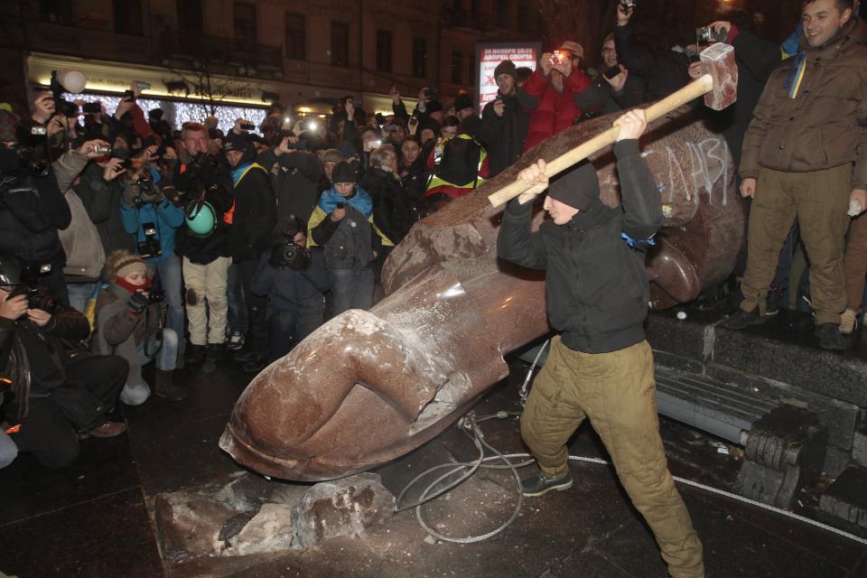 FILE - In this file photo taken on Sunday, Dec. 8, 2013, an anti-government protester beats the statue of Vladimir Lenin with a sledgehammer in Kiev, Ukraine. A former Soviet republic on the fault line between Russia and Europe is boiling with revolt this summer. Sounds familiar — but Belarus 2020 isn’t Ukraine 2014, and that’s why it’s hard to predict what will happen next. (AP Photo/Sergei Chuzavkov)