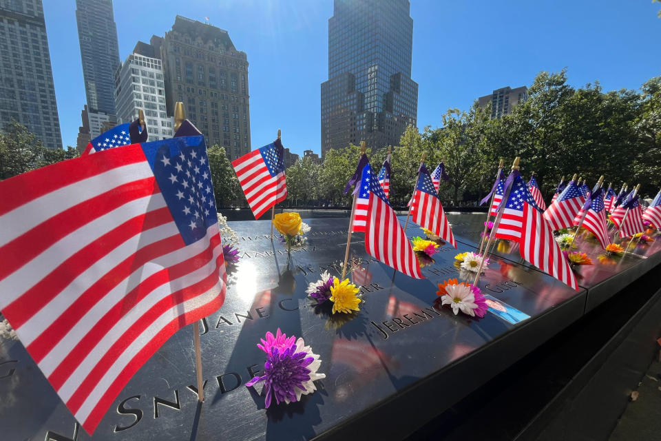 Flags and flowers are placed by the names of those killed during the Sept. 11, 2001, attacks at the reflecting pools at the National September 11 Memorial & Museum, Tuesday, Sept. 10, 2024, in New York. (AP Photo/Donald King)