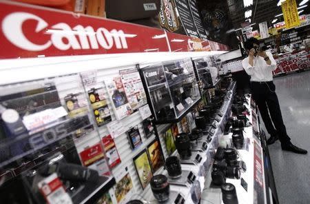 A man tries a Canon digital camera at an electronics retail store in Tokyo July 24, 2014. REUTERS/Yuya Shino