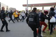 French gendarmes chase migrants near a closed petrol station who gather as they attempt to access the Channel Tunnel in Calais, France, July 30, 2015. REUTERS/Pascal Rossignol