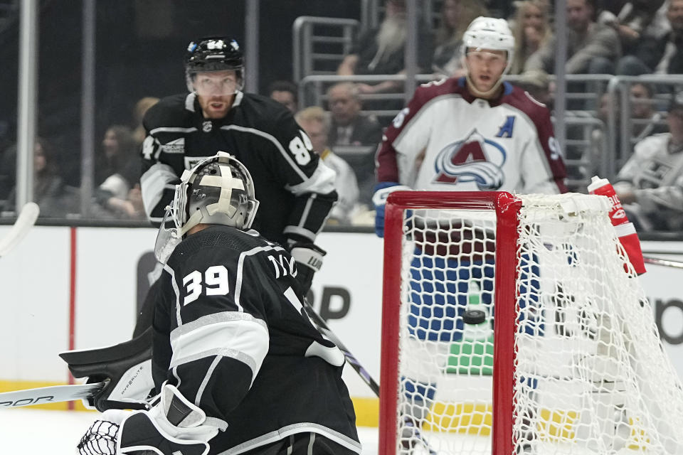 Los Angeles Kings goaltender Cam Talbot, left, is scored on by Colorado Avalanche center Nathan MacKinnon as defenseman Vladislav Gavrikov, center, and right wing Mikko Rantanen watch during the first period of an NHL hockey game Wednesday, Oct. 11, 2023, in Los Angeles. (AP Photo/Mark J. Terrill)