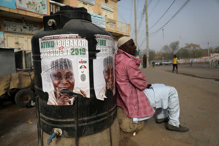 FILE PHOTO: A man sits next to a campaign poster of Atiku Abubakar, leader of the People's Democratic Party (PDP), after the postponement of the presidential election in Kano, Nigeria February 17, 2019. REUTERS/Luc Gnago/File Photo