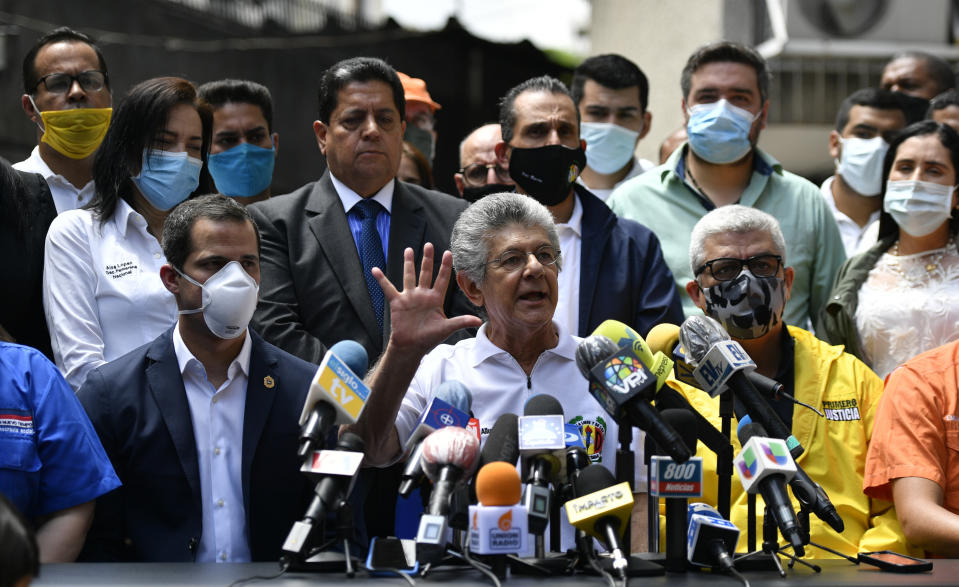 FILE - In this June 17, 2020 file photo, Venezuelan opposition leader Juan Guiado, sitting left, listens as Henry Ramos Allup, president of the Democratic Action political party, gives a press conference in Caracas, Venezuela, the day after Venezuela's Supreme Court ordered the party's takeover ahead of parliamentary elections expected this year. Some wear masks due to the COVID-19 pandemic. (AP Photo/Matias Delacroix, File)