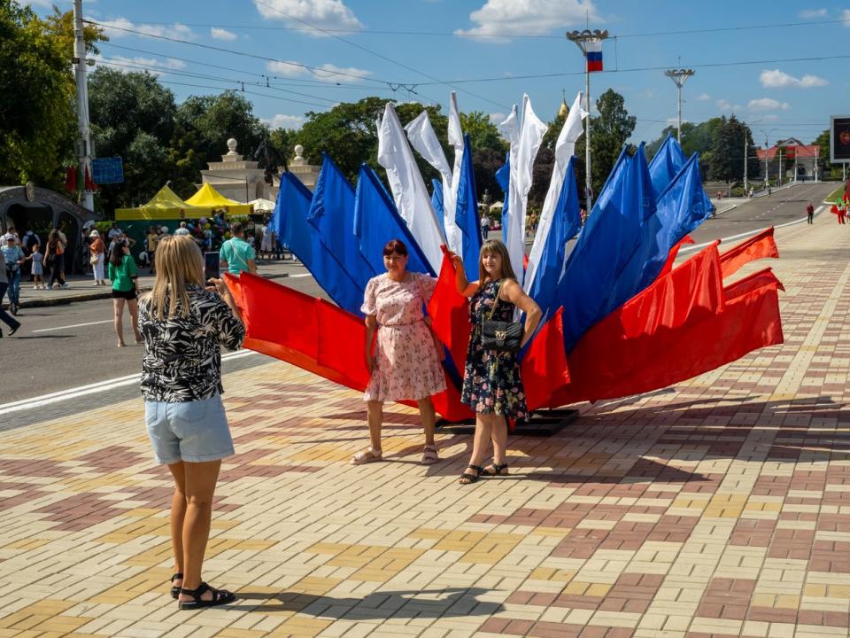 People pose for a photograph next to decoration in the colours of the Russian flag on Sept. 2, 2023 in Tiraspol, Moldova. (Peter Dench/Getty Images)