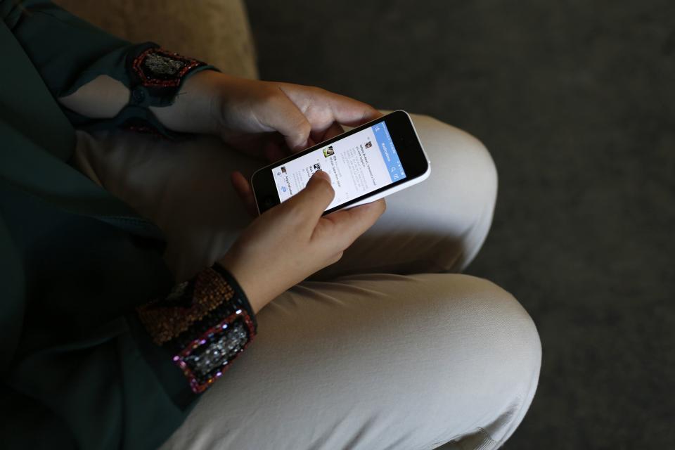 Farah Baker, 16, uses her phone to tweet in her family's home in Gaza City, August 10, 2014. As bombs explode in Gaza, Palestinian teenager Farah Baker grabs her smartphone or laptop before ducking for cover to tap out tweets that capture the drama of the tumult and fear around her. The 16-year-old's prolific posts on Twitter have made her a social media sensation through the month-old conflict. Once a little known high school athlete, Baker's following on the Web site has jumped from a mere 800 to a whopping 166,000. Picture taken August 10, 2014. REUTERS/Siegfried Modola (GAZA - Tags: SCIENCE TECHNOLOGY CONFLICT POLITICS CIVIL UNREST)