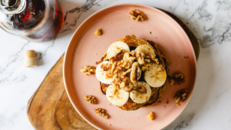 stack of pancakes with bananas and walnuts in plate