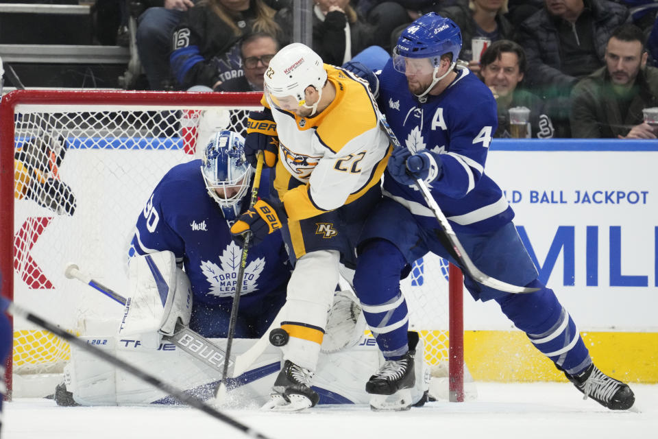 Toronto Maple Leafs defenseman Morgan Rielly (44) tries to clear Nashville Predators right wing Nino Niederreiter (22) from out in front of Maple Leafs goaltender Matt Murray (30) during the second period of an NHL hockey game, Wednesday, Jan. 11, 2023 in Toronto. (Frank Gunn/The Canadian Press via AP)