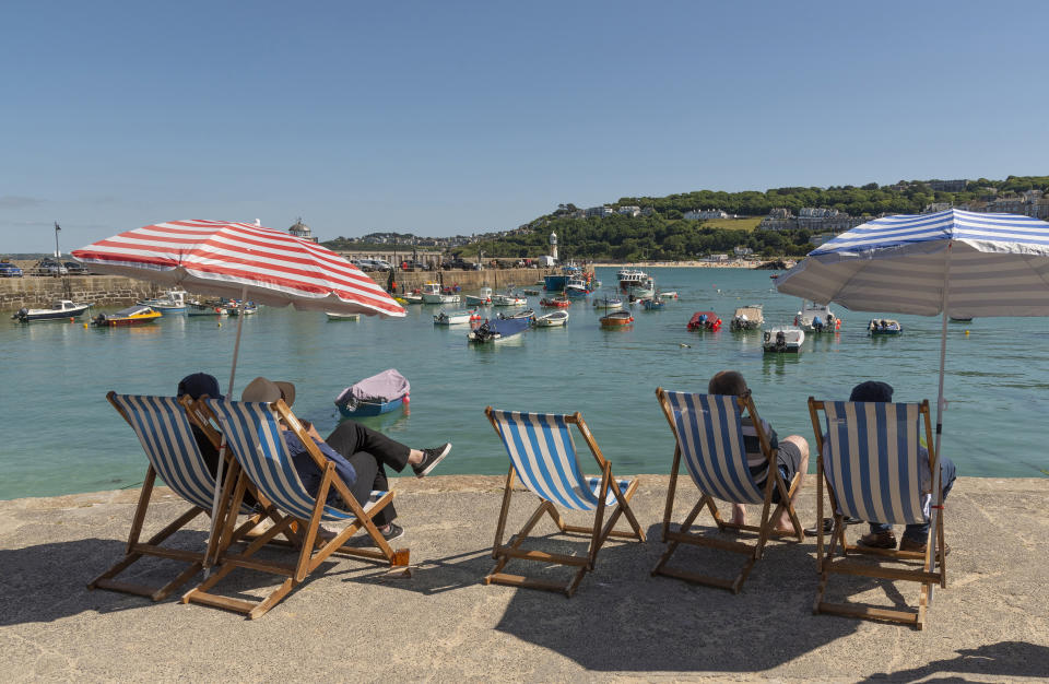 happiest  St Ives, Cornwall, England, UK, Holidaymakers relax in deck chairs on the harborside looking towards Porthminster beach. St Ives famous holiday resort.. (Photo by: Peter Titmuss/UCG/Universal Images Group via Getty Images)