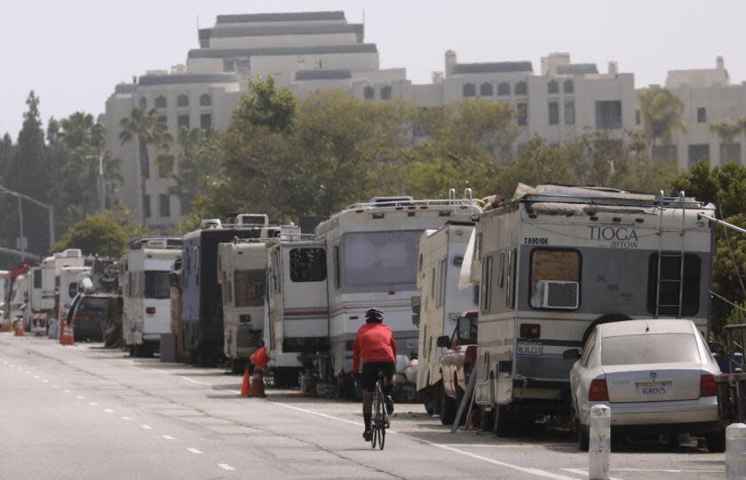 MARINA DEL REY, CA - MAY 24, 2022 - - A bicyclist rides past a line of campers that make up the Balloon Creek homeless encampment along Jefferson Boulevard in Marina Del Rey on May 24, 2023. A new LAPD report links RV encampments with increased crime in the surrounding areas and mentions the Ballona Creek encampment as problematic. (Genaro Molina / Los Angeles Times)