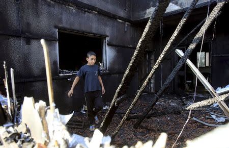 A Palestinian boy inspects a house that was badly damaged from a suspected attack by Jewish extremists on two houses at Kafr Duma village near the West Bank city of Nablus July 31, 2015. REUTERS/Abed Omar Qusini