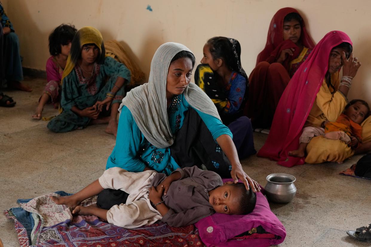 A woman takes care of her child as she with other families take shelter in a school after fleeing from their villages of costal areas due to Cyclone Biparjoy approaching, in Gharo near Thatta, a Pakistan’s southern district in the Sindh province (AP)