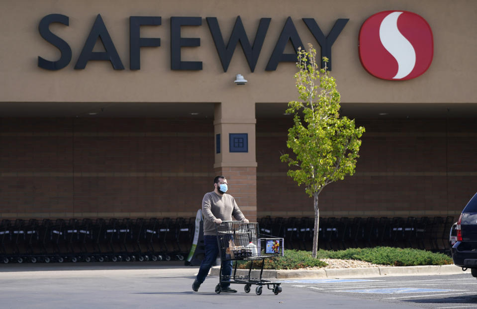 In this Wednesday, May 19, 2021, photograph, a shopper wearing a face covering uses a cart to wheel his purchases to a vehicle at a Safeway grocery store in Aurora, Colo. Many workers in retail sales jobs who are fully vaccinated are now concerned about risks posed as retailers change their mask-wearing policies for customers. (AP Photo/David Zalubowski)