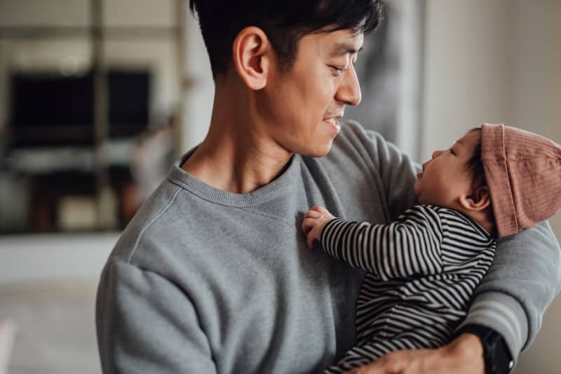 Smiling father shot holding his baby daughter looking at each other