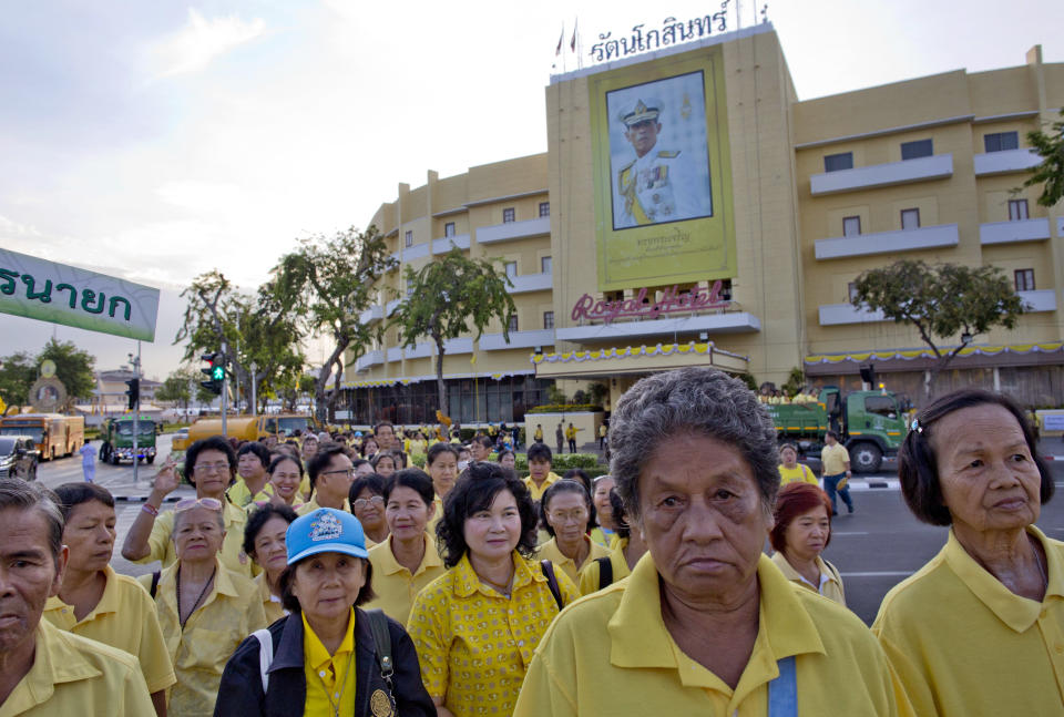 Thai people dressed in yellow walk past a portrait of Thailand's King Maha Vajiralongkorn towards the Grand Palace in which King Maha Vajiralongkorn's coronation takes place on Sunday, May 5, 2019, in Bangkok. Thailand's King Maha Vajiralongkorn was officially crowned Saturday amid the splendor of the country's Grand Palace, taking the central role in an elaborate centuries-old royal ceremony that was last held almost seven decades ago.(AP Photo/Gemunu Amarasinghe)