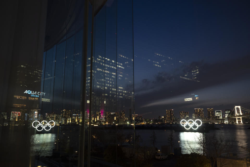 The Olympic rings are reflected in the glass wall of a wedding chapel in the Odaiba section of Tokyo, Monday, March 23, 2020. The Tokyo Olympics are going to happen — but almost surely in 2021 rather than in four months as planned. (AP Photo/Jae C. Hong)