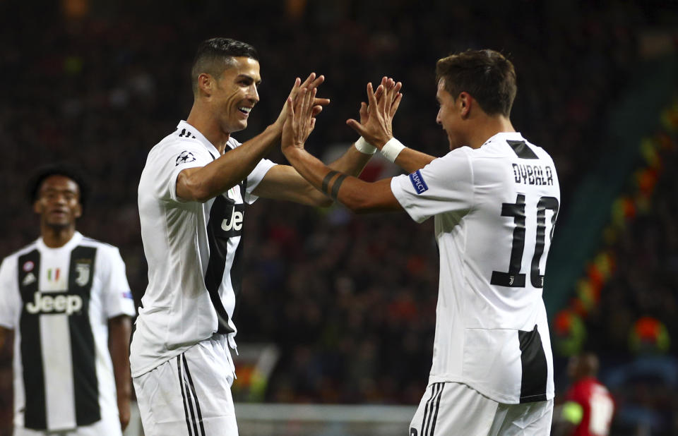 Juventus forward Paulo Dybala, right, celebrates with Juventus forward Cristiano Ronaldo after scoring the opening goal during the Champions League group H soccer match between Manchester United and Juventus at Old Trafford, Manchester, England, Tuesday, Oct. 23, 2018. (AP Photo/Dave Thompson)