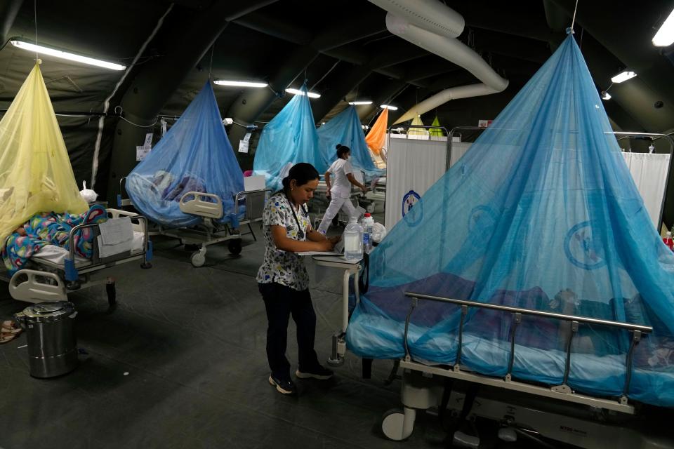 A doctor writes a prescription as patients suffering from dengue lie in beds in provisional tents at the Health Ministry in Piura, Peru, Saturday, June 3, 2023. Dengue, a viral disease transmitted by a mosquito, causes flu-like symptoms, such as muscle pain and fever. (AP Photo/Martin Mejia)