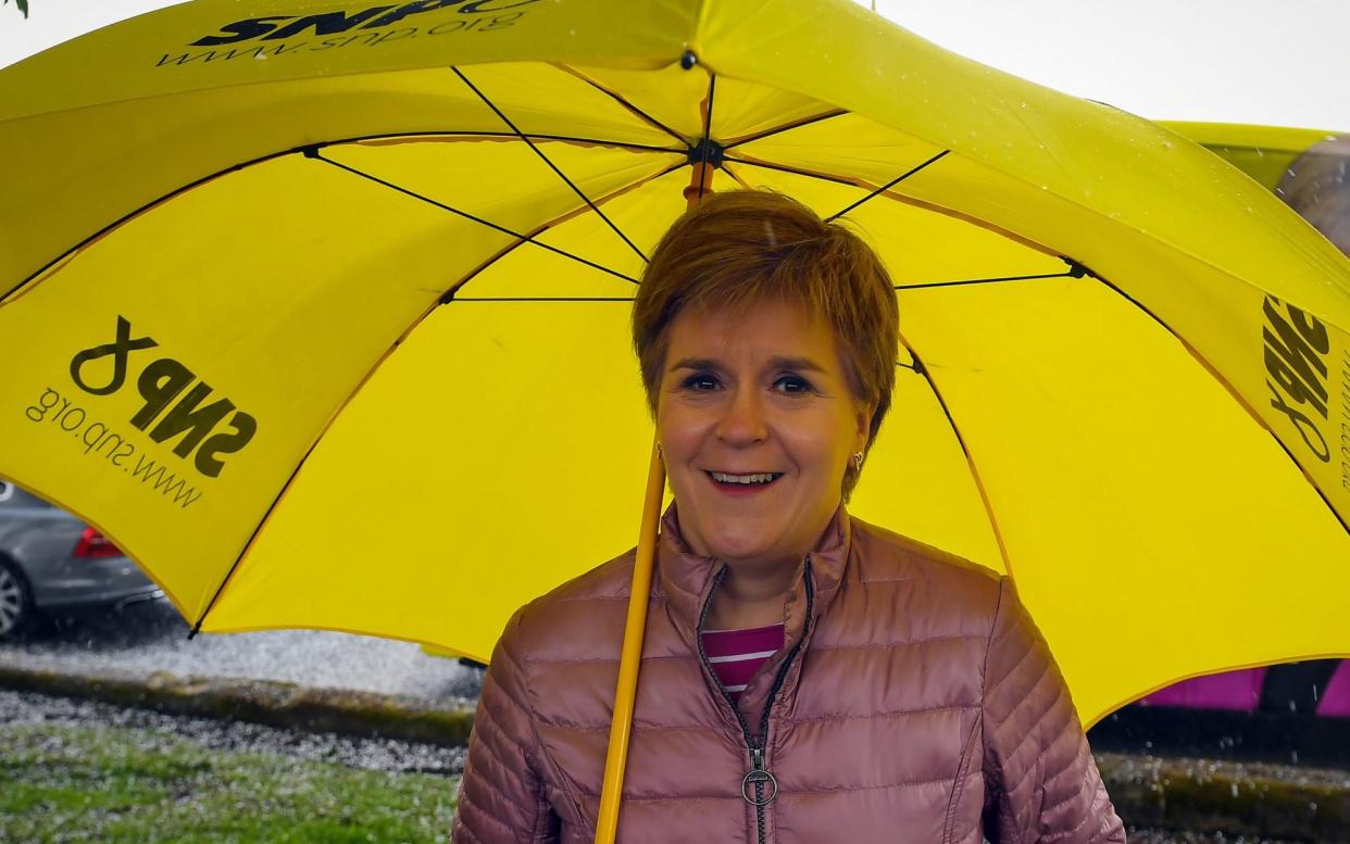 DUMBARTON, SCOTLAND - APRIL 14: Scotland's First Minister and leader of the Scottish National Party (SNP), Nicola Sturgeon stands under an umbrella as she campaigns on April 14, 2021 in Dumbarton, Scotland. The Scottish National Party (SNP) is the largest political party in Scotland with 125,691 members and 61 MSPs in the Holyrood parliament. They stand on a centre-left platform advocating an independent Scotland, nuclear disarmament and social democracy. Scottish voters go to the polls to elect their parliament on May 6, 2021. (Photo by Andy Buchanan - Pool/Getty Images - Andy Buchanan/Pool/Getty Images