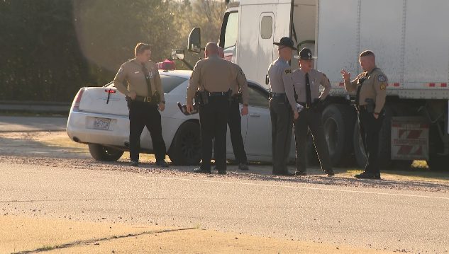 Responding officers investigate near a white sedan and a white semi truck at the scene were an arrest was made in a child abduction case in Raleigh on Thursday. (Michael Barnard/CBS 17)