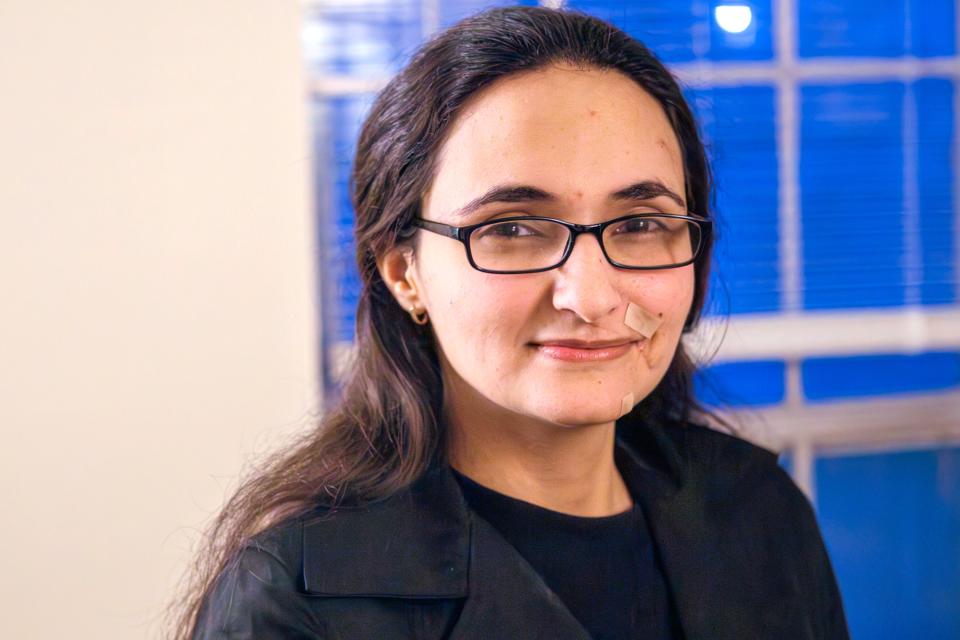 Hanan Shaheen wears black and glasses and smiles a little.