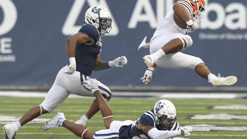 Idaho State running back Raiden Hunter (5) leaps over Utah State cornerback Gabriel Bryan as safety Anthony Switzer helps defend during the first half of an NCAA college football game Saturday, Sept. 9, 2023, in Logan, Utah. 