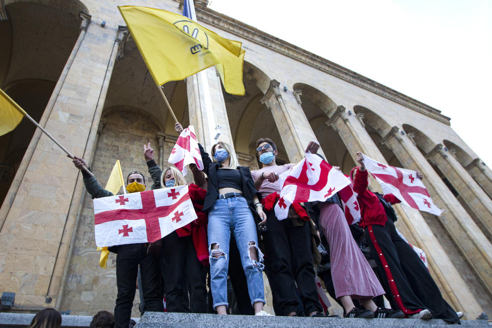 Supporters of the ex-President Mikhail Saakashvili's United National Movement, most of them wearing face masks to help curb the spread of the coronavirus, wave Georgian national and movement flags during rally to protest the election results, in front of the parliament's building in Tbilisi, Georgia, Sunday, Nov. 1, 2020. Preliminary election results show that Georgia's ruling party won the country's highly contested parliamentary election, but the opposition have refused to recognize Sunday's results. (AP Photo/Shakh Aivazov)