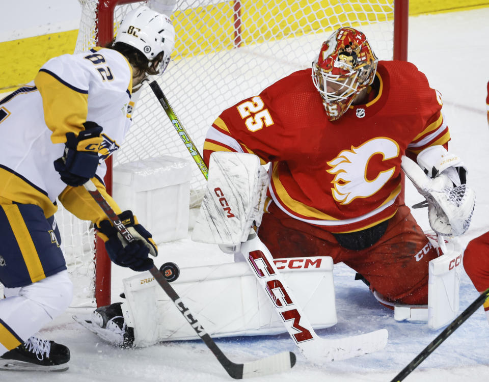Nashville Predators forward Tommy Novak, left, has his shot stopped by Calgary Flames goalie Jacob Markstrom (25) during the second period of an NHL hockey match in Calgary, Alberta, Tuesday, Nov. 7, 2023. (Jeff McIntosh/The Canadian Press via AP)